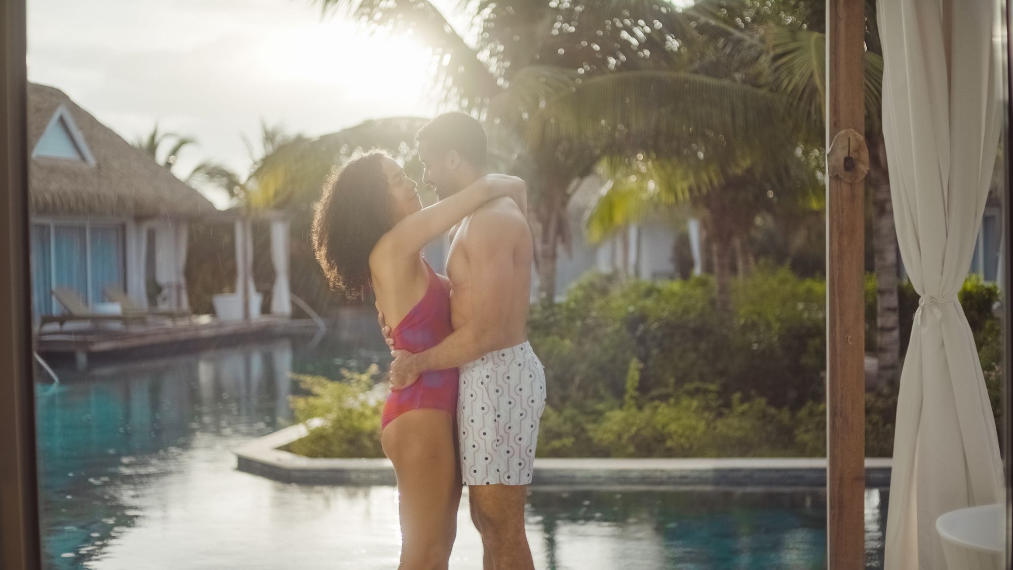 couple standing by pool hugging in swimwear