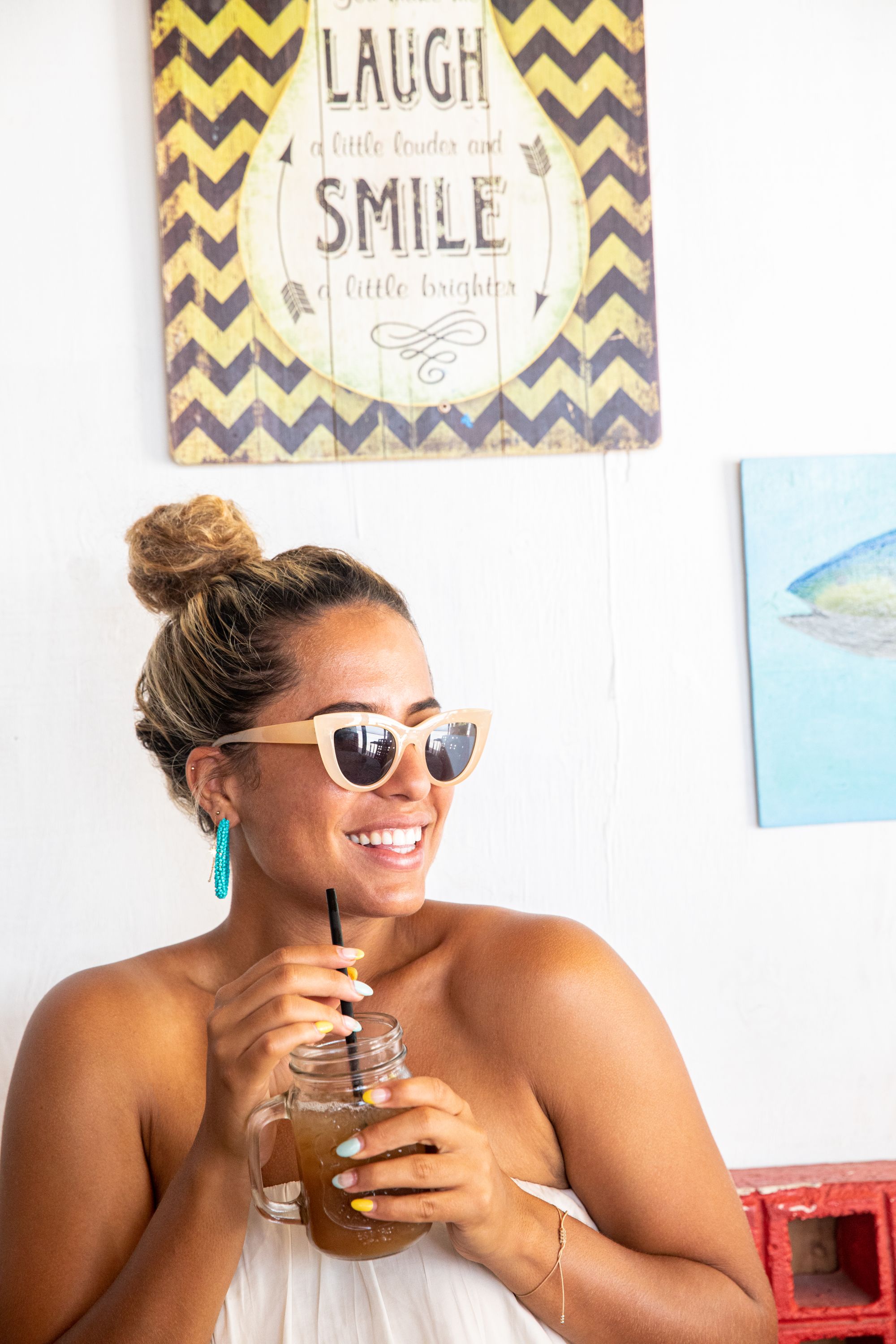 woman wearing sunglasses drinking iced tea from a mason jar with a straw