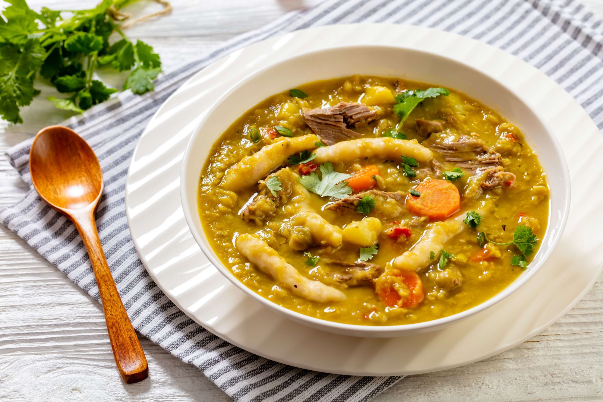 Gungo-peas-soup served in a white bowl with a wooden spoon laid on table