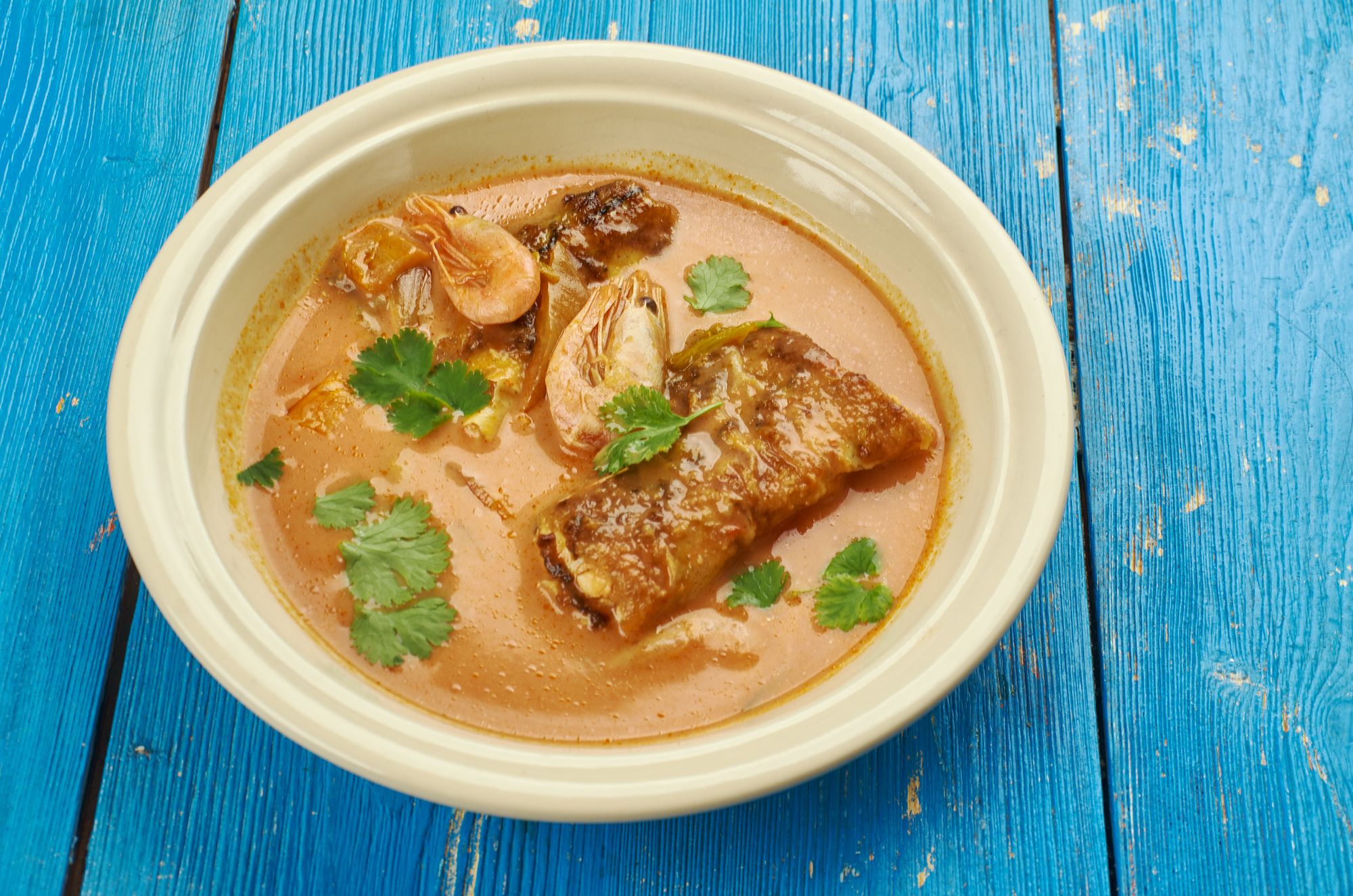 creamy fish stew with shrimp and mackeral and green garnish