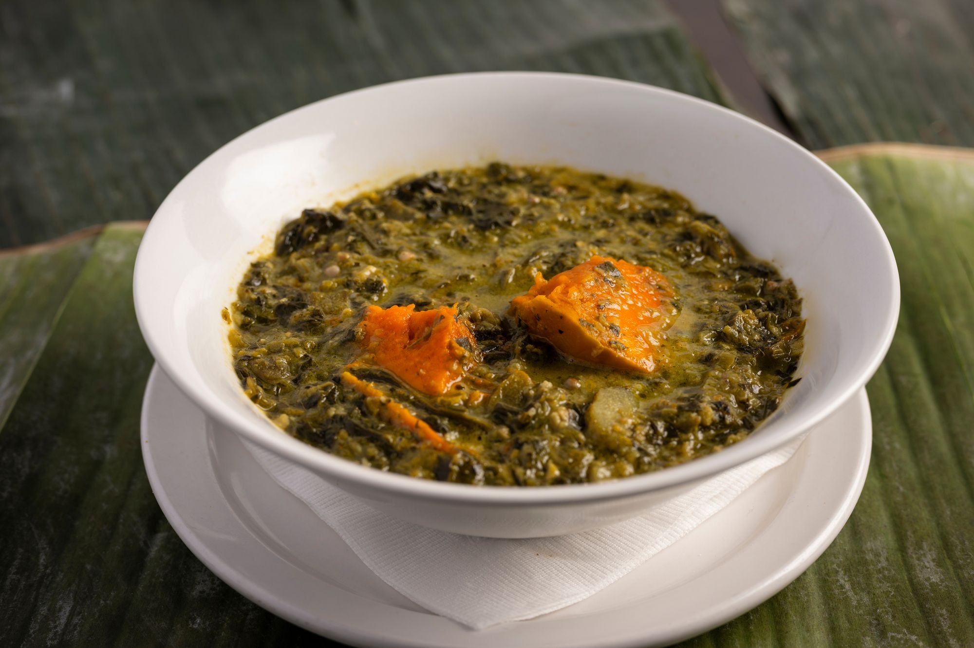 calloo soup with sweet potato served in a white bowl