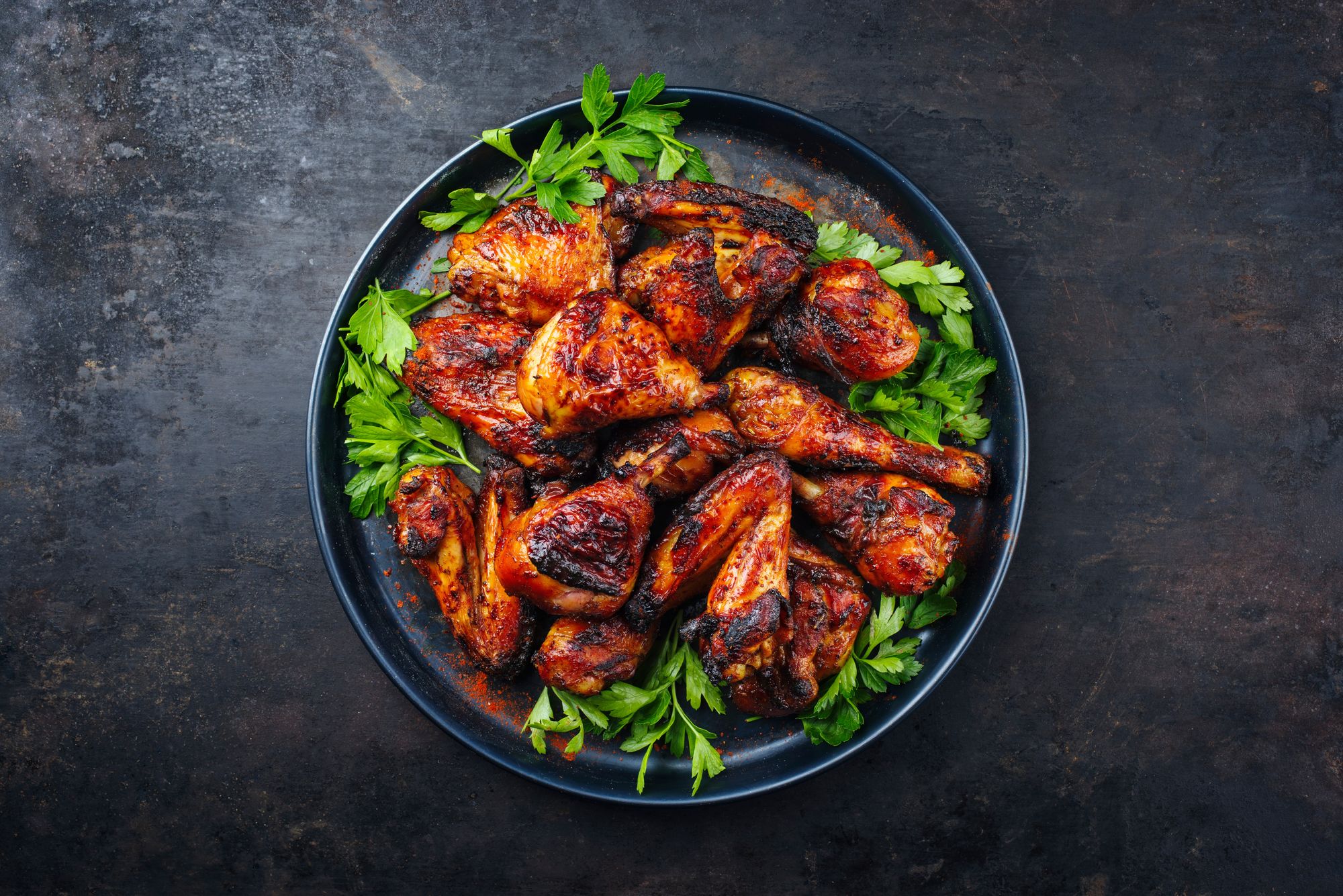 jerk chicken on a black plate with green garnish