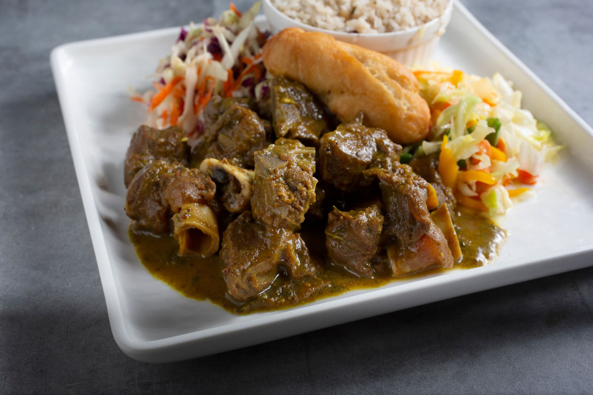 plate with goat curry mutton with rice and coleslaw